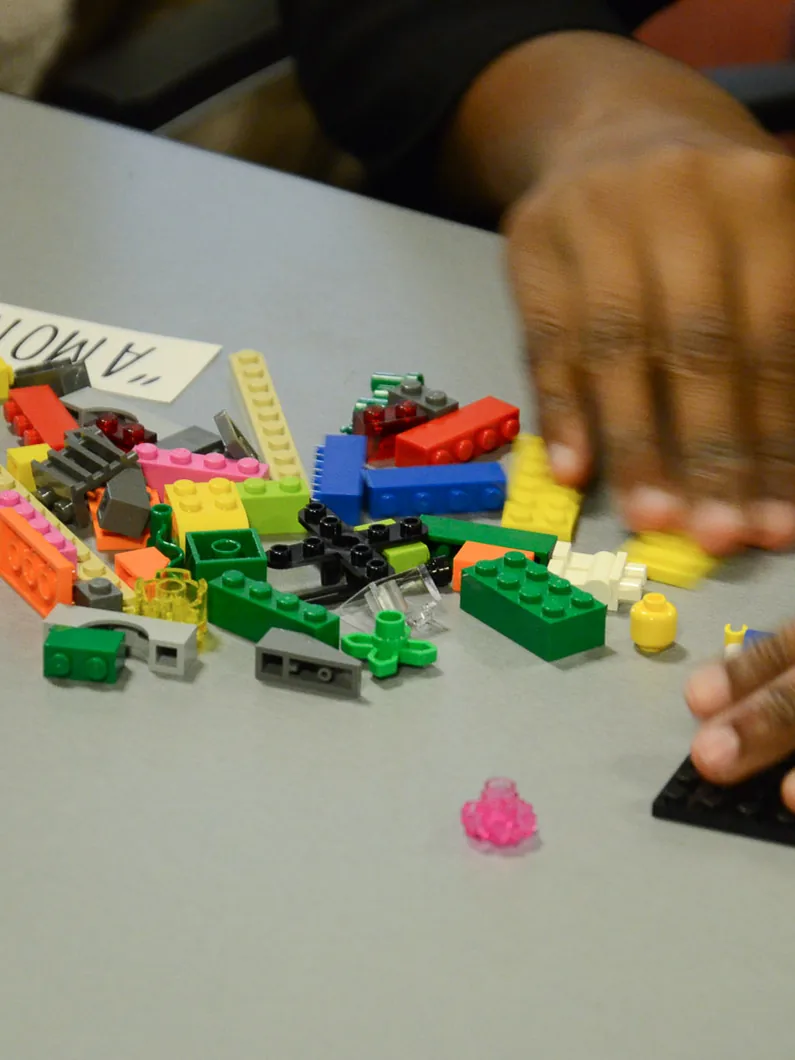 Mains construisant un modèle en briques colorées