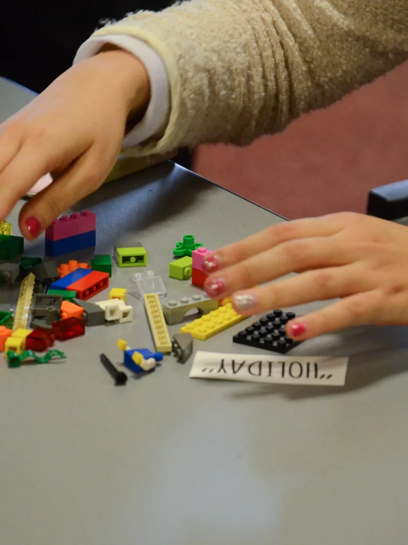 Mains assemblant des briques colorées