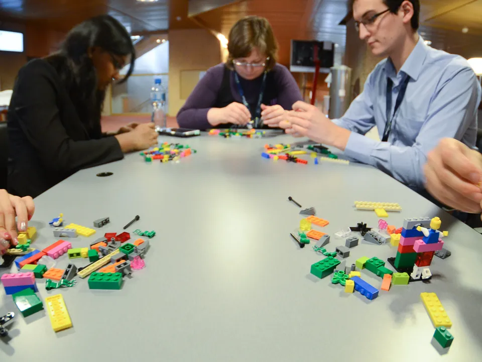 Trois participants construisant avec des briques colorées