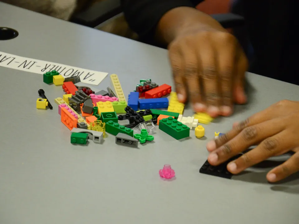 Mains construisant un modèle en briques colorées
