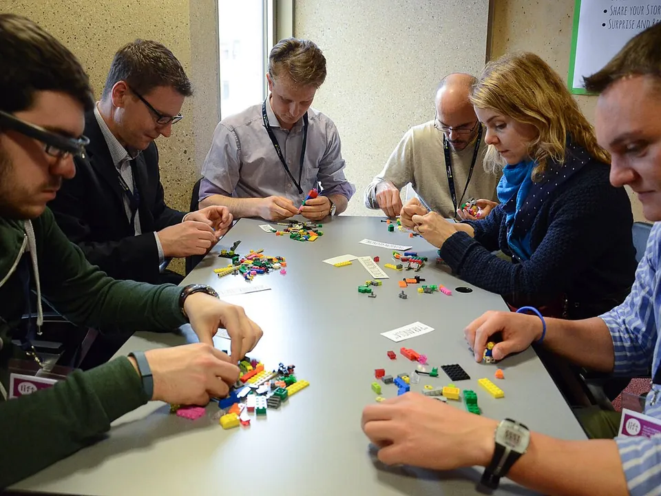 Participants construisant des modèles en briques autour d'une table