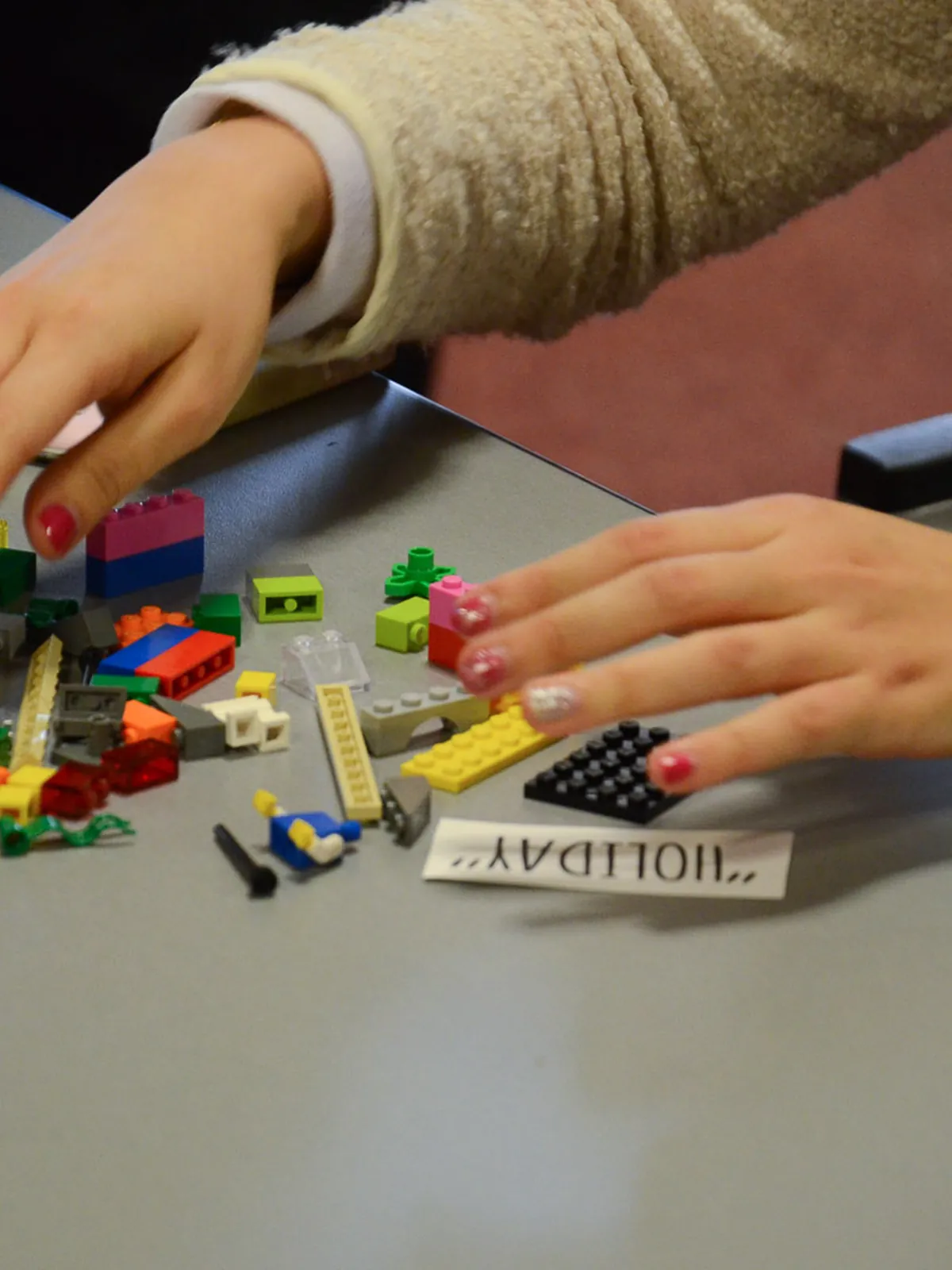 Mains assemblant des briques colorées sur une table d'atelier